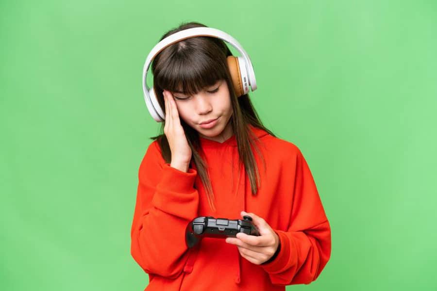 Picture of a Gamer Girl experiencing headache while playing video games.