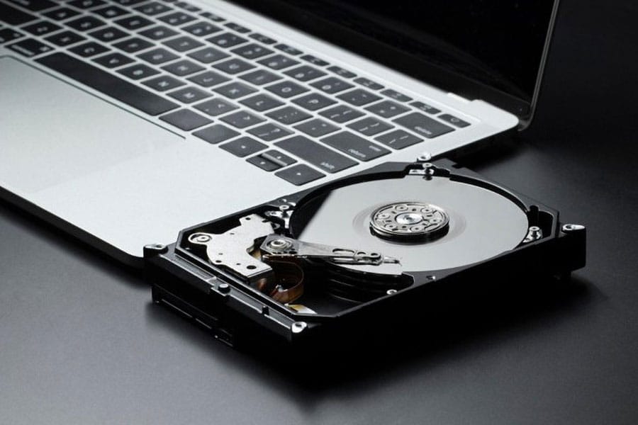 Picture of hard drive next to a laptop.