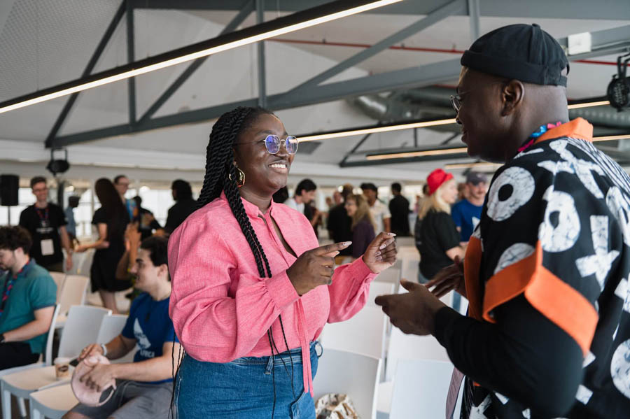 a black woman and a black man talking in a hall of Africa Games Week 2024.