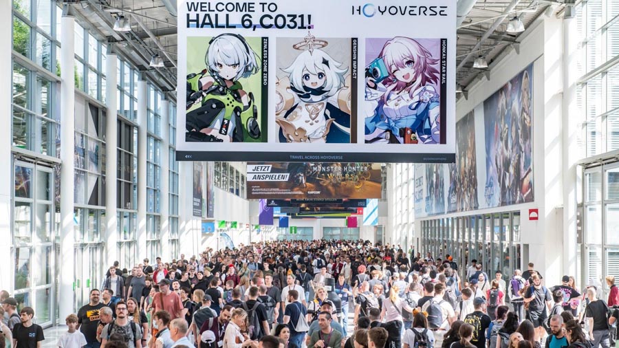 hall full of people in festival of Gamescom 2025 with a screen advertising anime game.